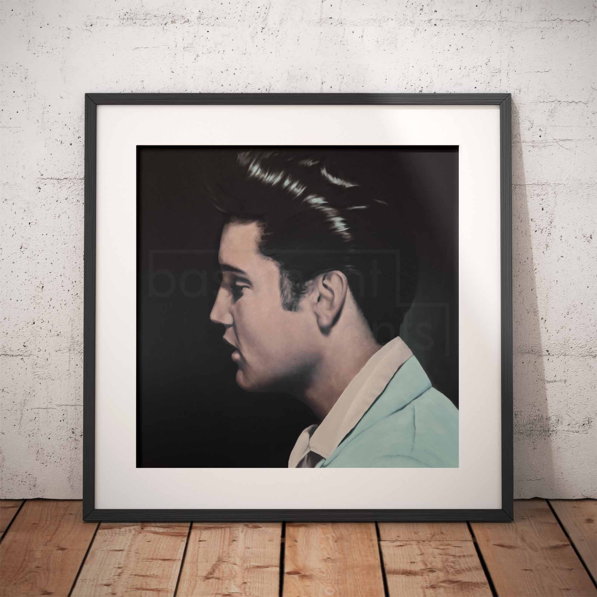 Framed portrait of Elvis Presley in profile against a dark background, leaning against a textured wall.