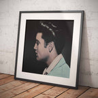 Framed portrait of Elvis Presley against a white brick wall.