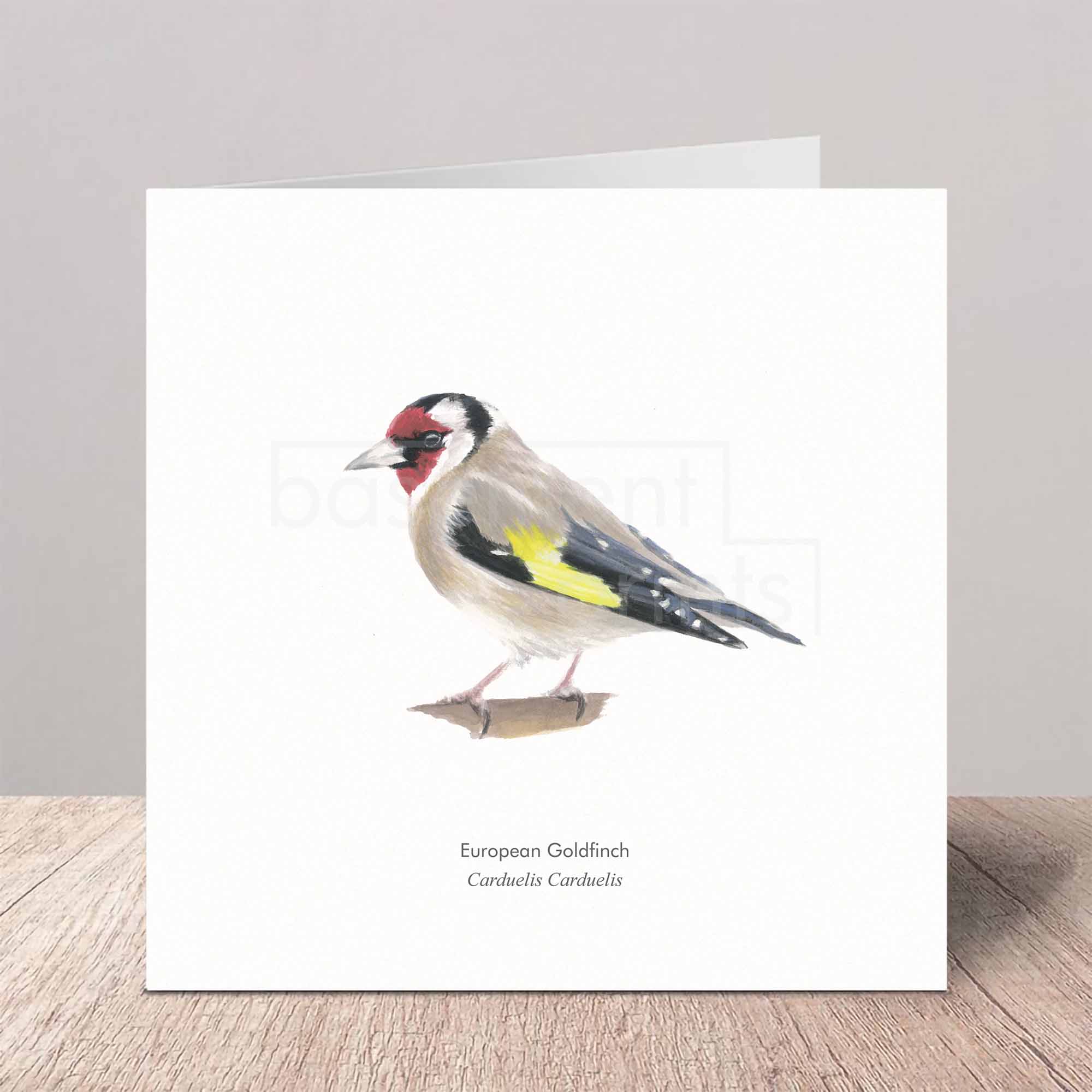 Greeting card with a watercolour illustration of a European Goldfinch on a wooden surface.