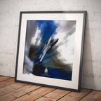 Framed artwork of an F35 Lightning II aircraft against a blue sky with clouds on a wooden floor.