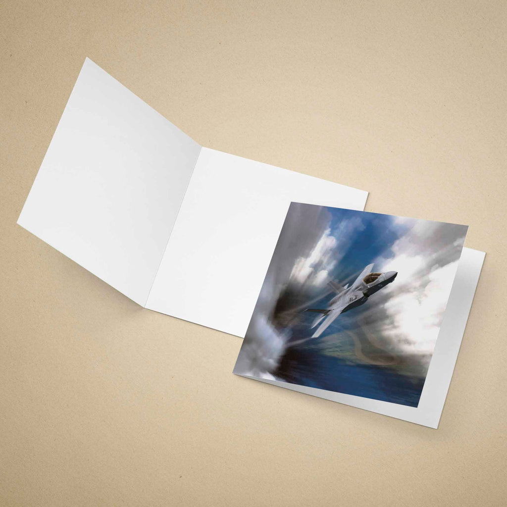 Greeting card with an F35 Lightning II aircraft on a dark background, placed inside an open white envelope on a beige surface.