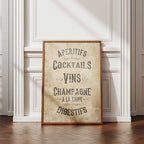 Framed poster with French drinks list on a wall in a room with wooden flooring.