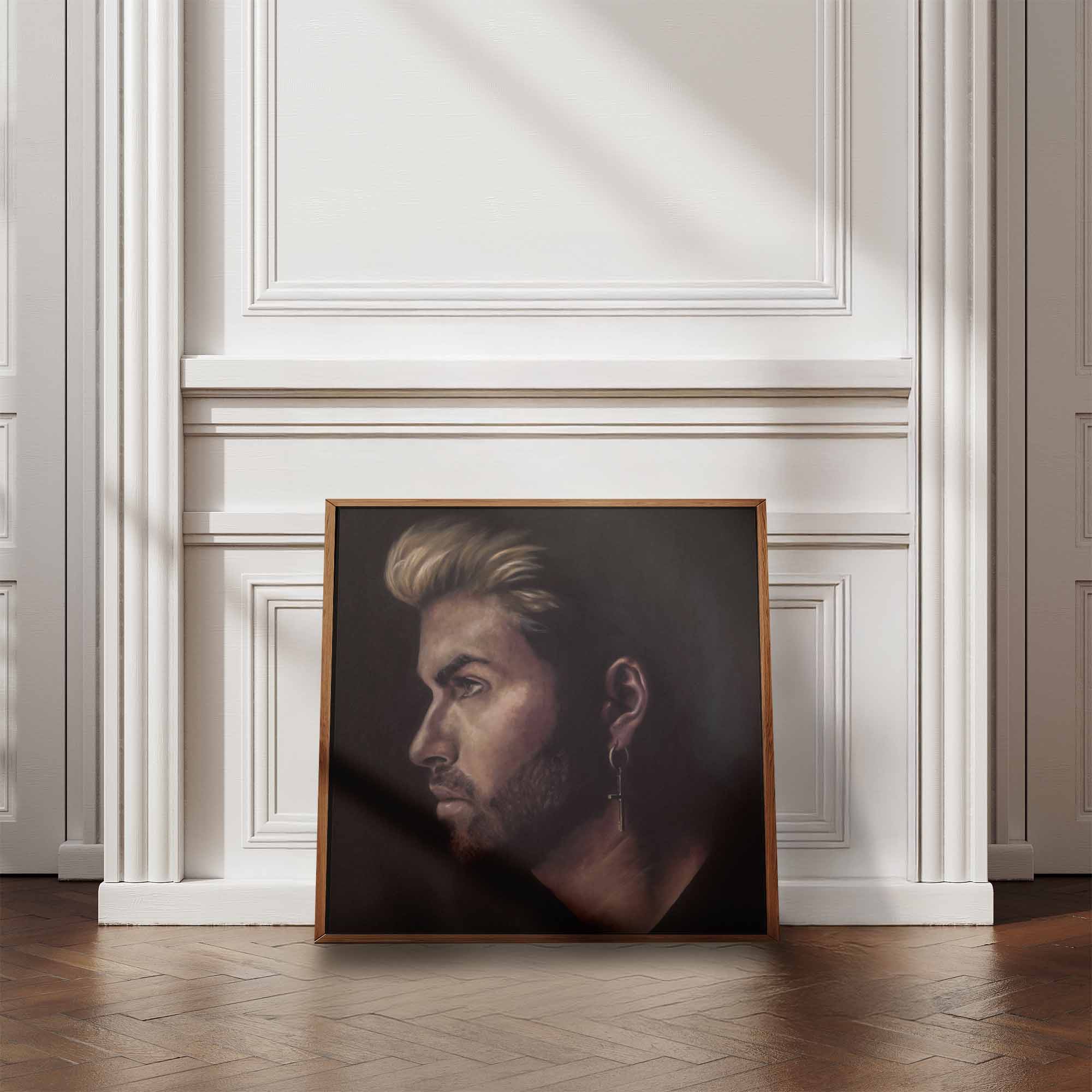 Framed portrait of George Michael on a white wall.