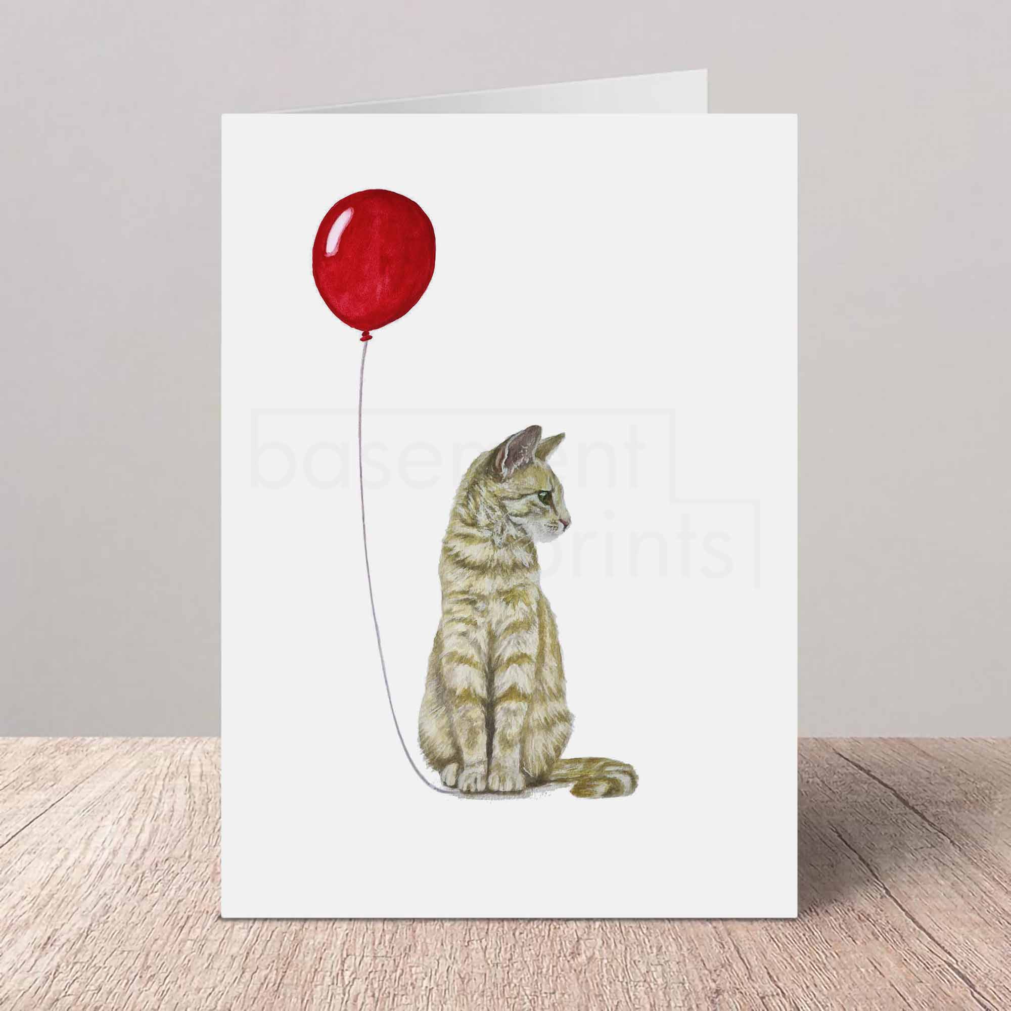 Greeting card with a ginger tabby cat and red balloon design on a white background