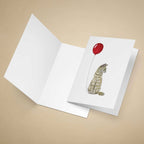Greeting card with a ginger tabby cat and red balloon design on a beige background
