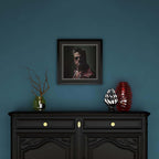 Framed portrait above a black cabinet with decorative items on a blue wall