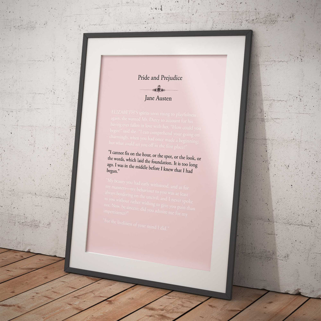 Framed print of 'Pride and Prejudice' by Jane Austen on a pink background against a white brick wall.