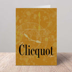 Greeting card with 'It's Clicquot time' text and clock design on a wooden surface.