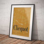 Framed Clicquot poster on a white brick wall with wooden floor