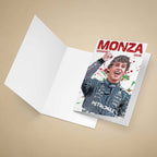 A folded white greeting card lies open on a beige background, with a printed front insert showing Kimi Antonelli in his race suit and the bold red text 'MONZA WINNER 2026' with paint-splatter accents.