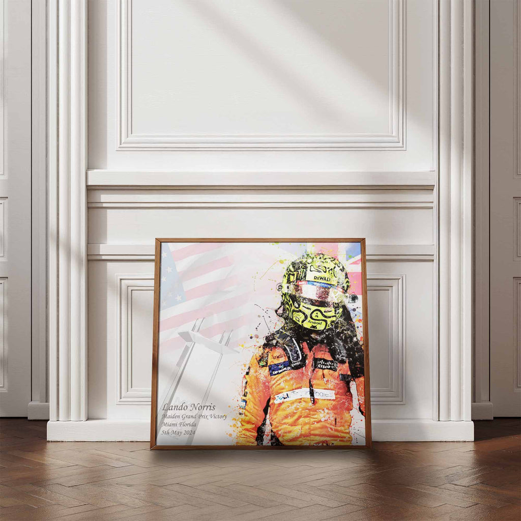 Framed artwork of  Lando Norris after his first Formula 1 Win on a wall with wooden flooring.