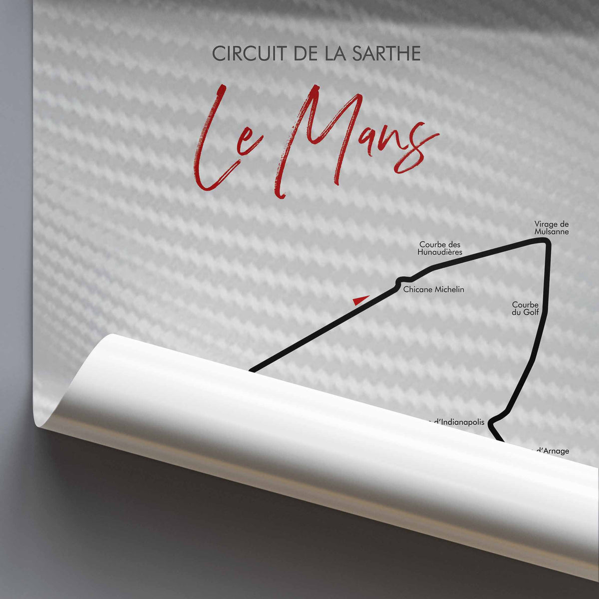 A rolled-up poster or print showing the Circuit de la Sarthe Le Mans race track, with a large red script title 'Le Mans' and black track-line illustration on a light gray background.