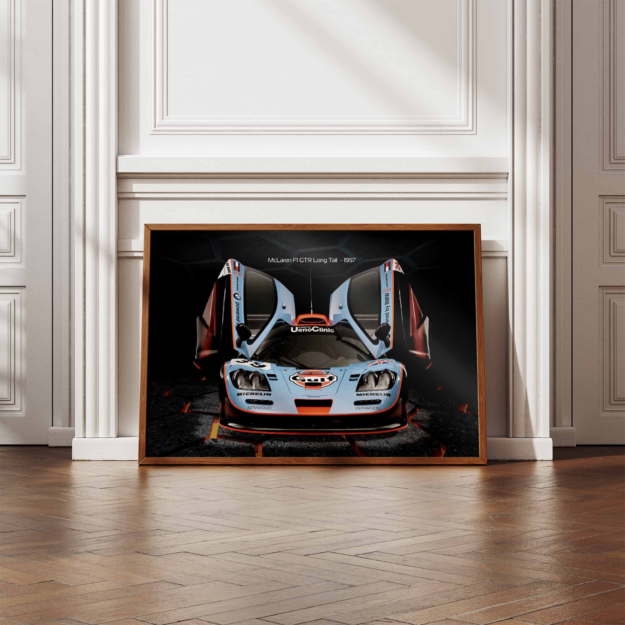 Framed print of a McLaren F1 GTR Gulf racing car on a white wall with wooden floor.