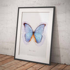 Framed artwork of a blue butterfly on a white background against a brick wall.