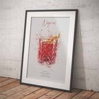 Framed print of a  Negroni cocktail illustration on a brick wall background with a wooden floor.