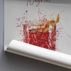 Rolled poster art print of a glass with negroni cocktail and orange splashes on a white background