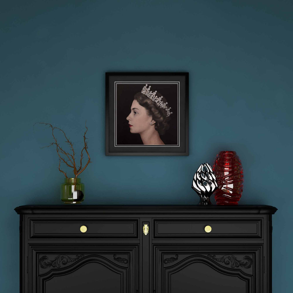 Framed artwork of Queen Elizabeth II above a black cabinet with decorative items against a blue wall
