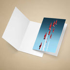 An open greeting card on a beige background, showing a printed cover image of The Red Arrows aircraft flying in formation against a blue sky with white contrails.