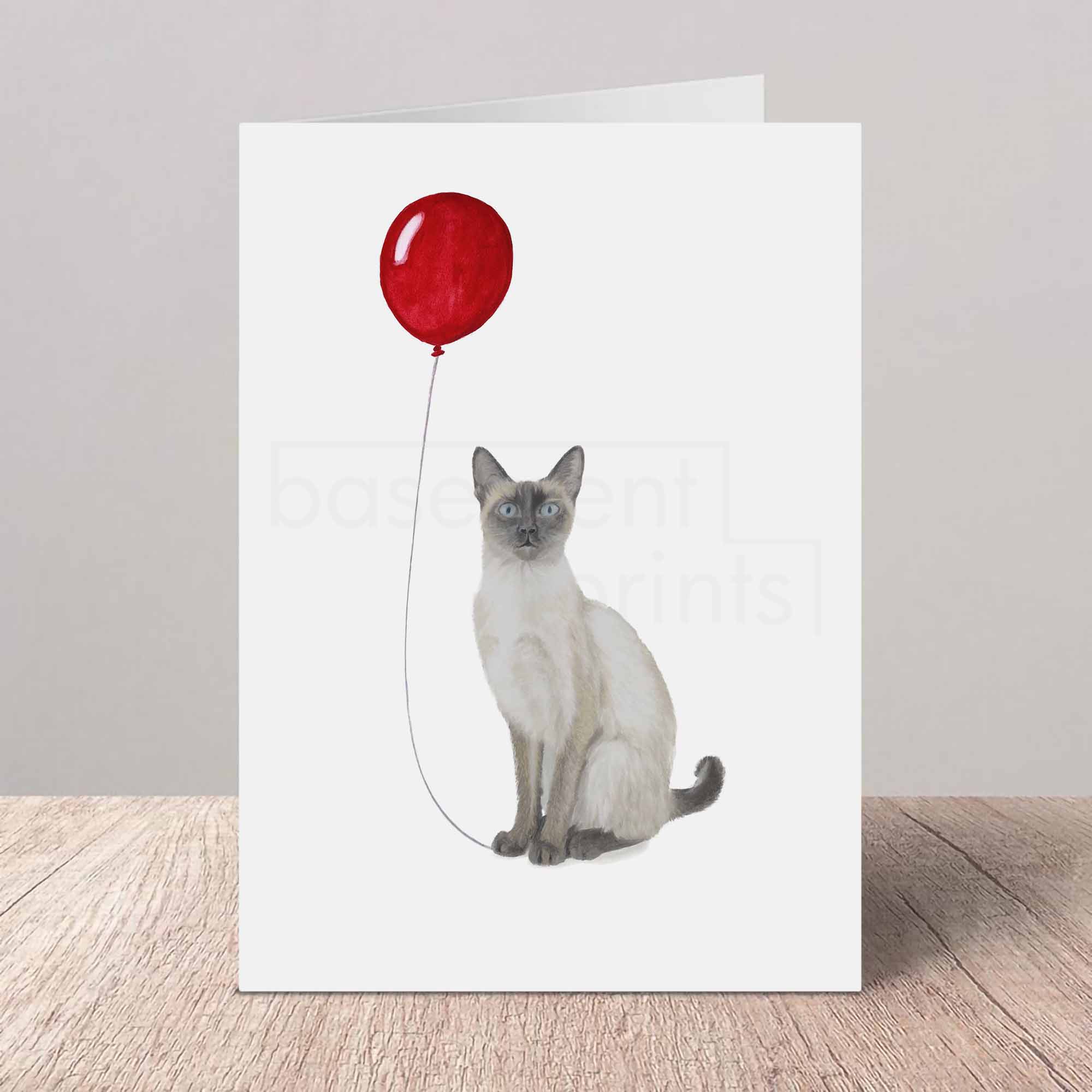 Greeting card with a cat holding a red balloon on a white background