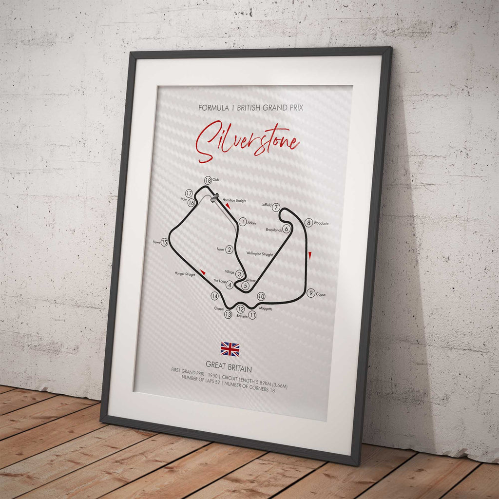 Framed poster of Silverstone circuit layout on a white brick wall.