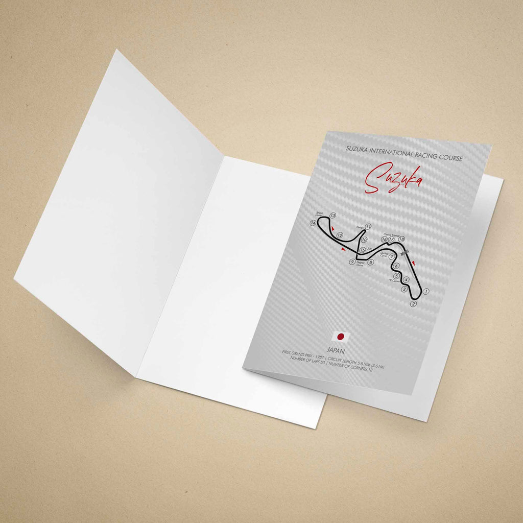A printed greeting card featuring a stylized Suzuka International Racing Course map with numbered turns, red script title 'Suzuka,' and course text, standing on a warm beige background.