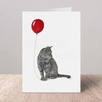 Greeting card with a grey tabby cat and red balloon design on a white background