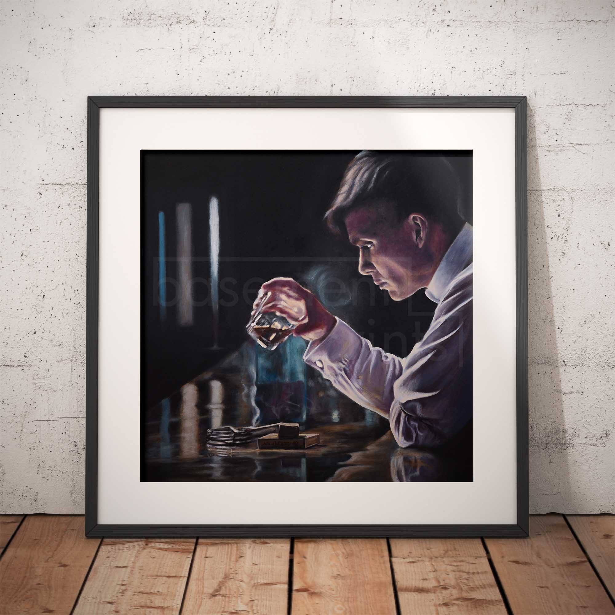 Framed artwork of Thomas Shelby from Peaky Blinders holding a whisky glass on a wooden floor with a white brick wall background.