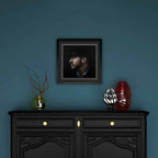 Framed portrait of Tom Hardy above a black cabinet with decorative items against a blue wall